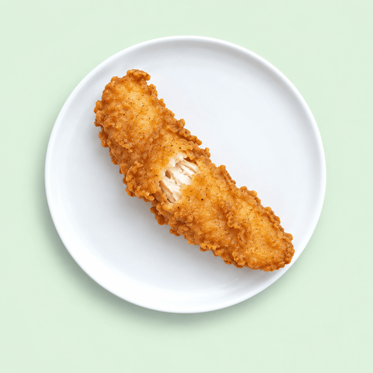 Golden battered chicken tender showing white chicken inside