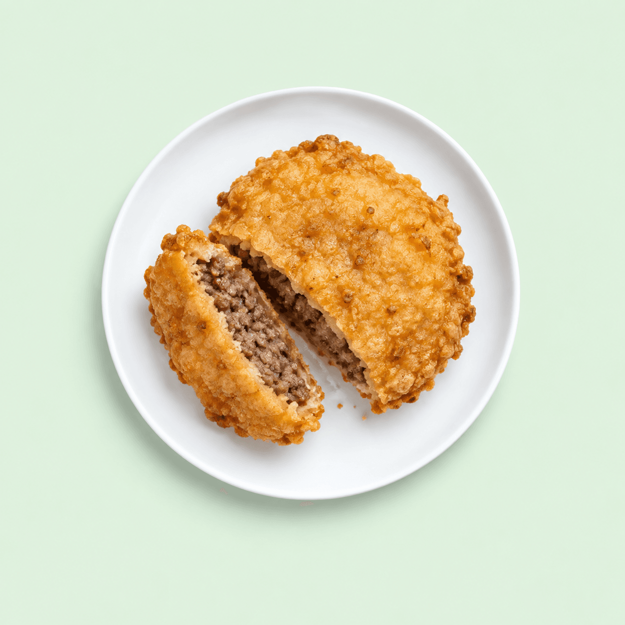 Golden battered meat patty cut open to show its filling