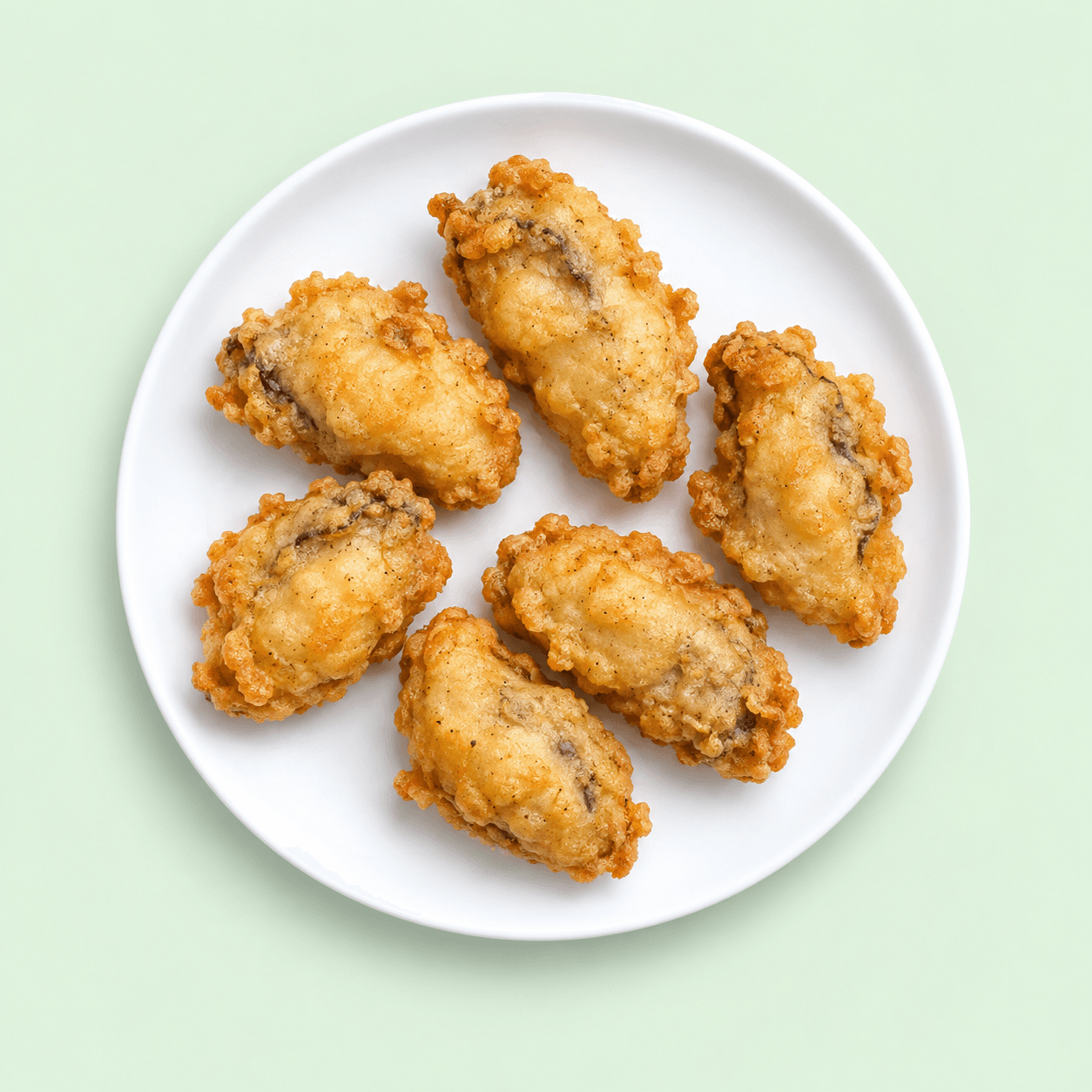 Six golden battered oysters on a white plate