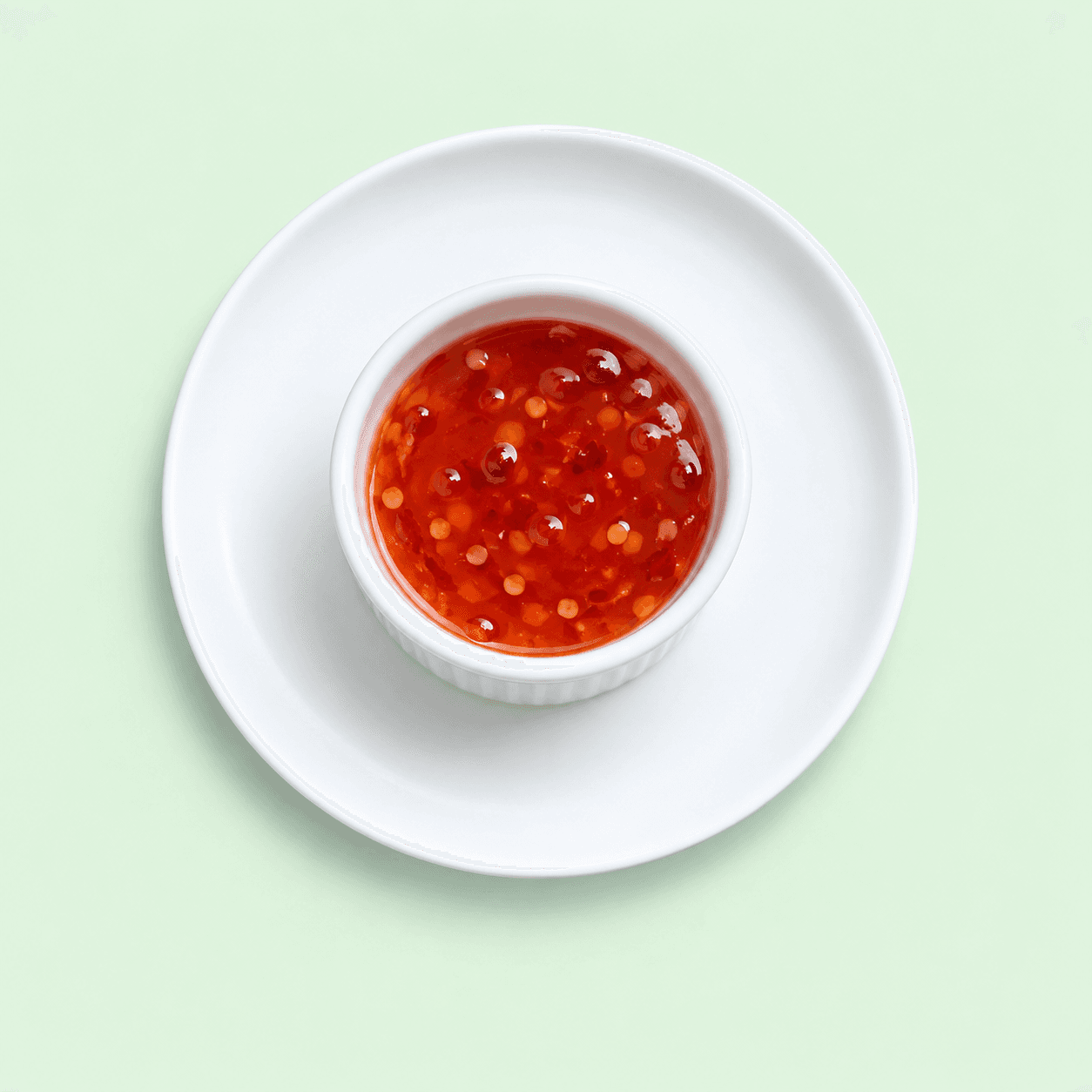 Red sweet chilli sauce in a small white ramekin