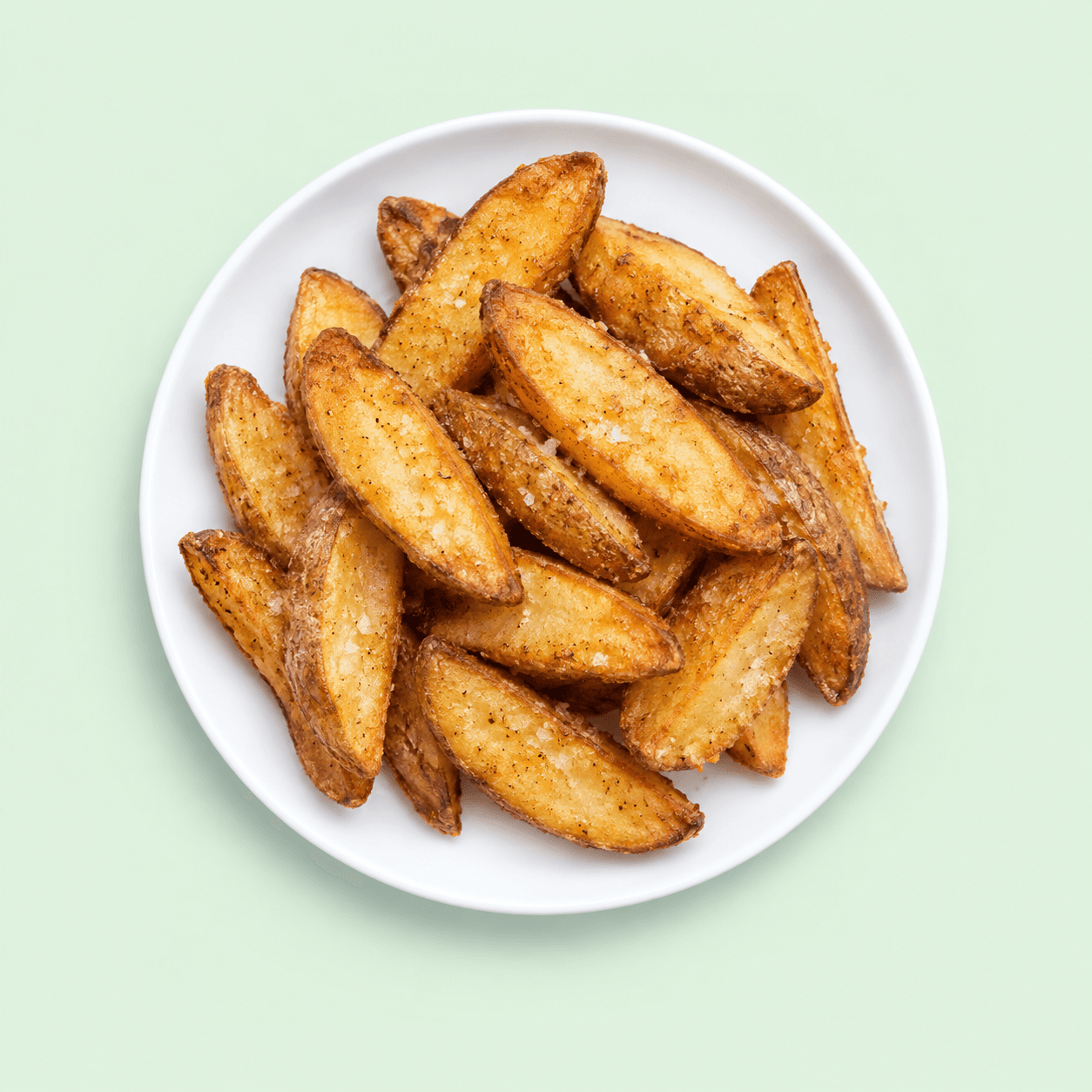 Seasoned golden potato wedges on a white plate